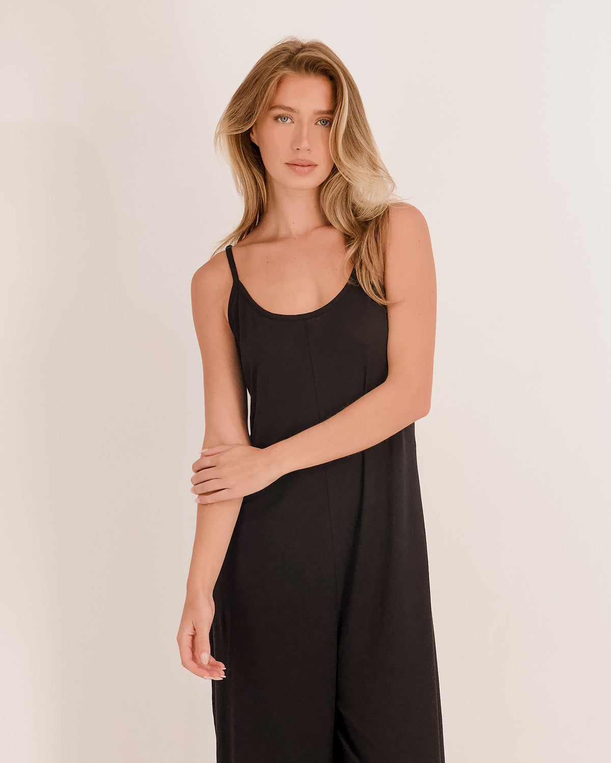 Model in black jumpsuit on beige background looking sultry